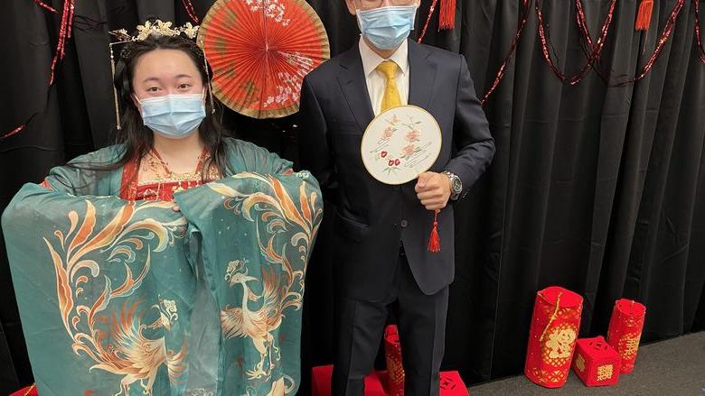 一名男学生穿着西装，一名女学生穿着中国传统服装.